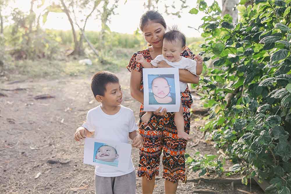 Jefferson smiles and holds up a photo of himself from before cleft treatment