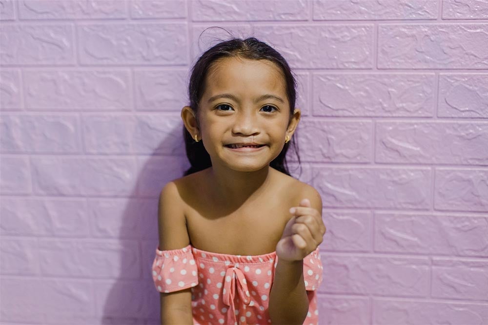 Leana smiling and making a heart symbol with her fingers