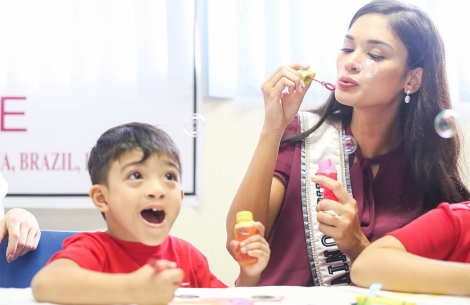 Miss Universe blows bubbles with happy child